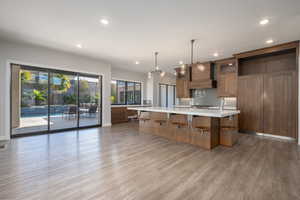 Kitchen featuring tasteful backsplash, a large island, a breakfast bar area, light wood-type flooring, and brown cabinets
