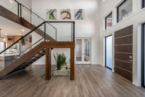Foyer entrance with wood finished floors, a high ceiling, stairs, and french doors