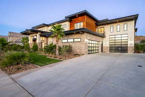 Contemporary house featuring concrete driveway, a garage, and a front lawn