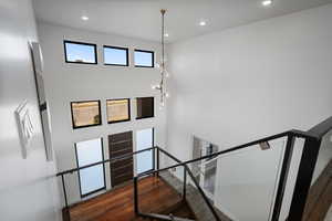 Staircase featuring wood finished floors, a towering ceiling, a chandelier, and recessed lighting