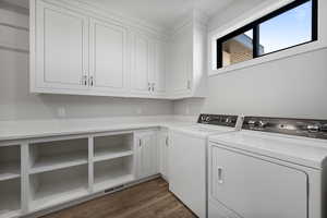 Laundry area featuring dark wood finished floors, independent washer and dryer, and cabinet space