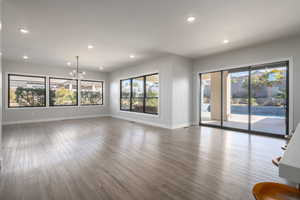Unfurnished living room with wood finished floors, recessed lighting, and a chandelier