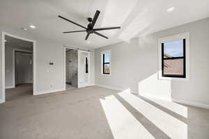 Unfurnished bedroom featuring a barn door, light colored carpet, recessed lighting, ceiling fan, and ensuite bathroom