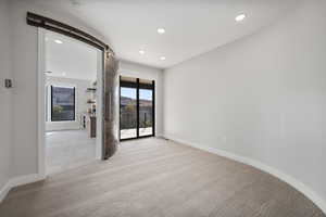 Empty room with a barn door, recessed lighting, and light carpet