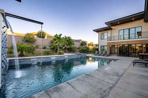 View of swimming pool with a balcony, a pool with connected hot tub, a fenced backyard, and a patio