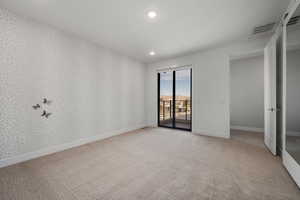 Empty room featuring wallpapered walls, recessed lighting, and light colored carpet