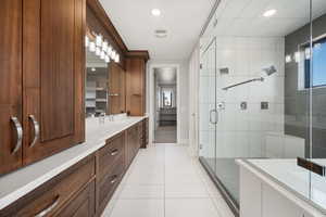 Full bath featuring a stall shower, double vanity, light tile patterned floors, recessed lighting, and healthy amount of natural light