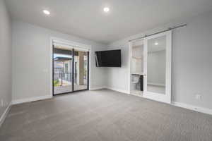 Unfurnished room with carpet flooring, recessed lighting, and a barn door