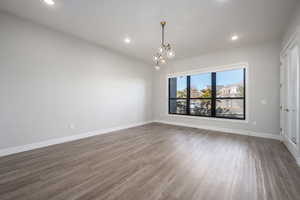 Unfurnished room featuring wood finished floors, recessed lighting, and a chandelier