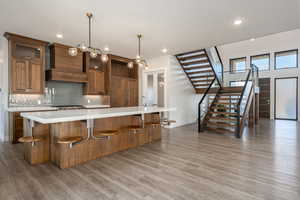 Kitchen with a breakfast bar, wood finished floors, a spacious island, pendant lighting, and recessed lighting