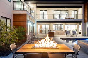 Back of house at twilight with a patio, outdoor dining space, a balcony, and a wooden deck