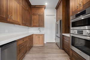 Kitchen with stainless steel appliances, light wood-style flooring, and brown cabinets