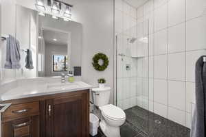 Full bath with vanity, walk in shower, and dark tile patterned flooring