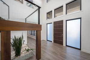 Entryway with wood finished floors and a towering ceiling