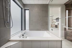Bathroom featuring a garden tub, tile walls, and light tile patterned flooring