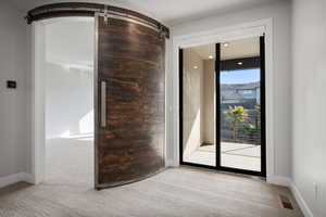 Spare room featuring a barn door and carpet flooring