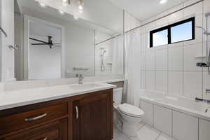 Bathroom with shower / bath combination with curtain, vanity, light tile patterned flooring, and a ceiling fan