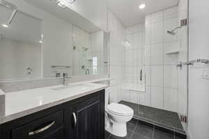 Bathroom featuring a shower stall, vanity, dark tile patterned floors, and recessed lighting