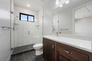 Full bath with a shower stall, vanity, dark tile patterned floors, and recessed lighting