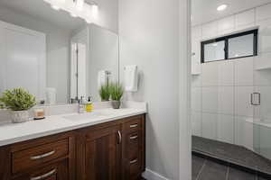 Full bath featuring a stall shower, vanity, and dark tile patterned flooring