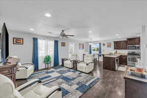Living area with dark wood-type flooring, recessed lighting, a ceiling fan, a chandelier, and a textured ceiling