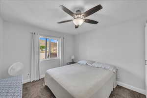 Bedroom featuring carpet floors, ceiling fan, and a textured ceiling