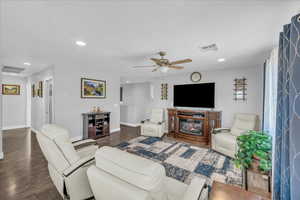 Living area with wood finished floors, a glass covered fireplace, recessed lighting, and ceiling fan