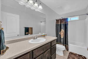 Bathroom featuring shower / bathtub combination with curtain, vanity, and light tile patterned flooring