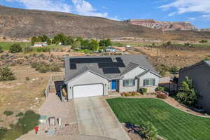 Ranch-style home with driveway, stucco siding, solar panels, a garage, and a mountain view