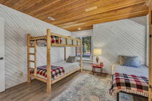 Bedroom featuring wooden walls, wooden ceiling, and wood finished floors