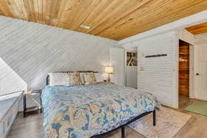 Bedroom featuring wooden walls, wood finished floors, and wooden ceiling