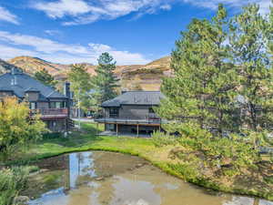 Back of house with a lawn and a deck with water view