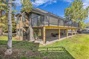 Back of house featuring a lawn, a deck, and a patio