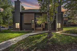 Contemporary home with a yard, entry steps, and a chimney