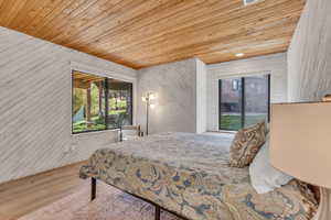Bedroom with wood ceiling, wood walls, wood finished floors, and recessed lighting