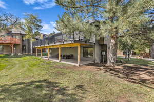 Rear view of house featuring a patio, a yard, and a wooden deck