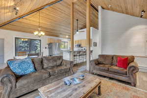 Living area featuring a chandelier, wood walls, wood finished floors, ceiling fan, and lofted ceiling