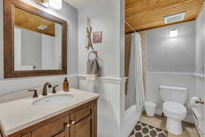 Bathroom with wooden ceiling, shower / bath combo with shower curtain, vanity, a baseboard heating unit, and a wainscoted wall