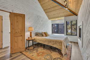 Bedroom featuring wooden walls, wood finished floors, wooden ceiling, and high vaulted ceiling