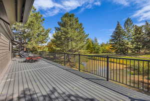 Wooden deck with outdoor dining space, view of wooded area, and a water view