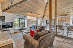 Living area featuring wood ceiling, wooden walls, a chandelier, light wood-style flooring, and high vaulted ceiling