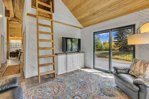 Living area with wood walls, wood ceiling, high vaulted ceiling, and wood finished floors