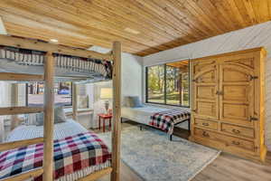 Bedroom with wooden ceiling, light wood-style flooring, and wood walls