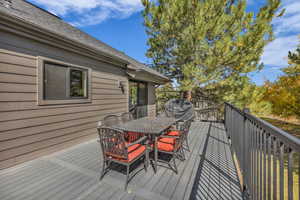 Wooden deck featuring outdoor dining area and a grill