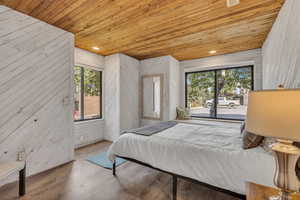 Bedroom featuring wooden ceiling, wooden walls, wood finished floors, access to exterior, and recessed lighting