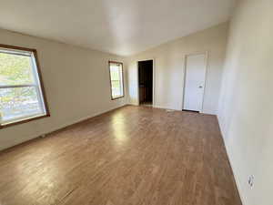 Primary bedroom featuring lofted ceiling and light wood-type flooring