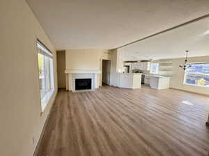 Living room with a fireplace, light wood-type flooring, a chandelier, a textured ceiling, and vaulted ceiling
