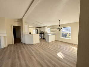 Living room featuring light wood-style floors, a chandelier, and a textured ceiling