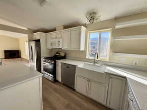 Kitchen featuring appliances with stainless steel finishes, dark wood-type flooring, lofted ceiling, a textured ceiling, and open floor plan