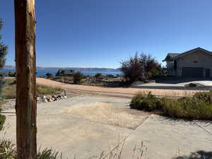 View of yard with driveway, a water view, and an attached garage